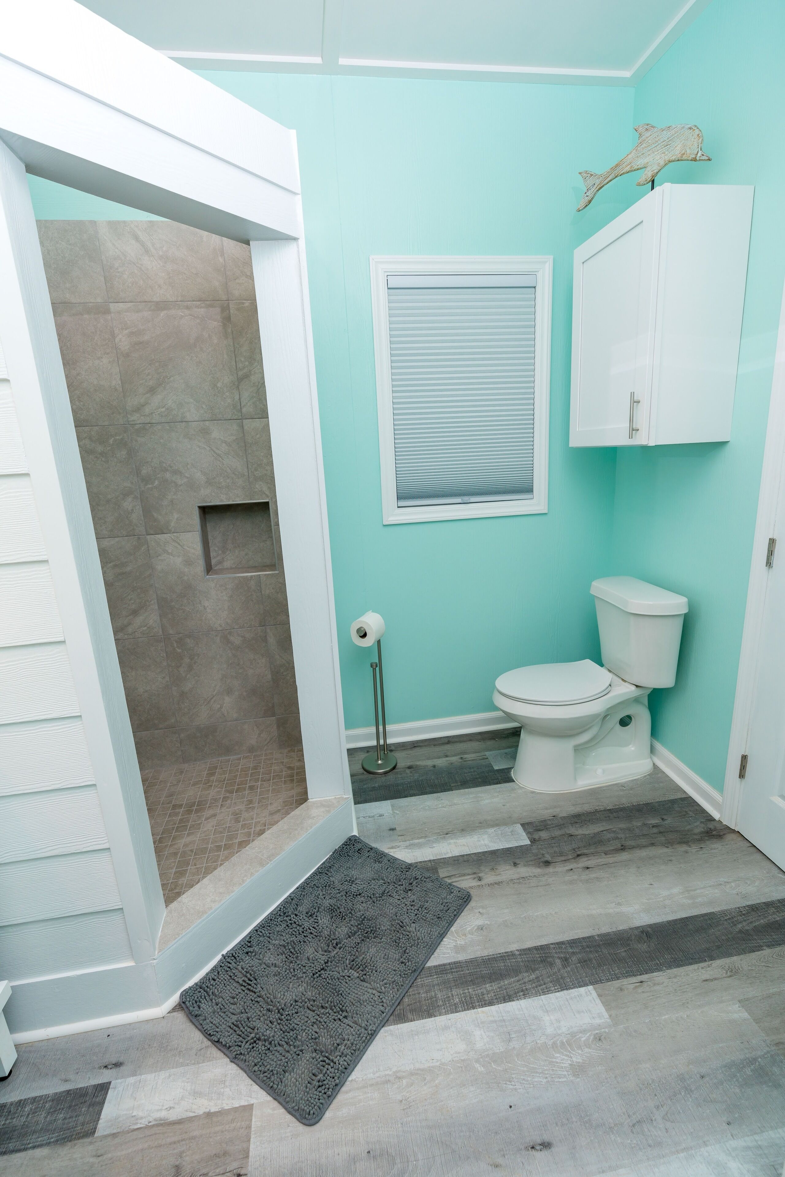 Une salle de bain avec une douche, des toilettes et une fenêtre.