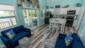 A modern kitchen with white cabinets, a refrigerator, and an oven. There is a dining area with a table and chairs. - Fish Fever, Russell Island Bahamas (Russell Island / Spanish Wells)