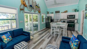 A spacious living area with a blue sofa, a dining table, and a kitchen area with white cabinets and appliances. - Fish Fever, Russell Island Bahamas (Russell Island / Spanish Wells)