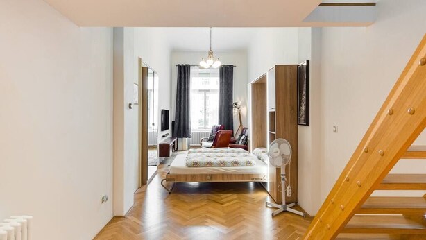 Een slaapkamer met een houten bed, een ventilator en een trap.