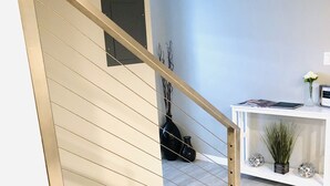 A modern interior with a staircase, a white console table with decorative items, and a minimalist decor style. - Family-Friendly, Renovated Suite (Extra Cleaning) (Orem)