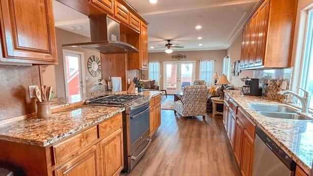 A spacious kitchen with wooden cabinets, granite countertops, a stove, and a dishwasher. - Steps to the Beach! Rooftop Deck! Firepit & BBQ! (Oceano)