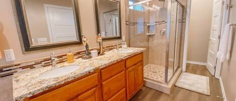 A bathroom with a double vanity, a glass shower enclosure, and a walk-in shower.