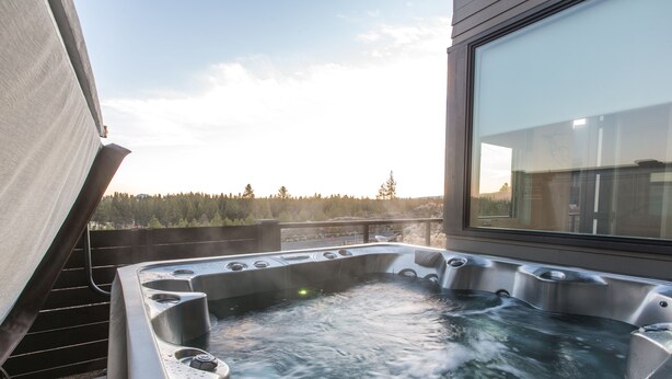 A hot tub with multiple jets, positioned on a balcony with a view of a forested landscape. - Luxury + views ~ 7 mins to downtown ~ resort ~ hot tub ~ wifi ~ BBQ ~ Bend ~ 🐶 (Bend)