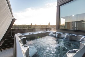 A hot tub with multiple jets, positioned on a balcony with a view of a forested landscape. - Luxury + views ~ 7 mins to downtown ~ resort ~ hot tub ~ wifi ~ BBQ ~ Bend ~ 🐶 (Bend)