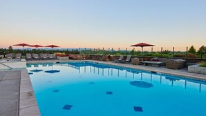 A swimming pool with lounge chairs and umbrellas, surrounded by a stone wall and greenery. - Luxury + views ~ 7 mins to downtown ~ resort ~ hot tub ~ wifi ~ BBQ ~ Bend ~ 🐶 (Bend)