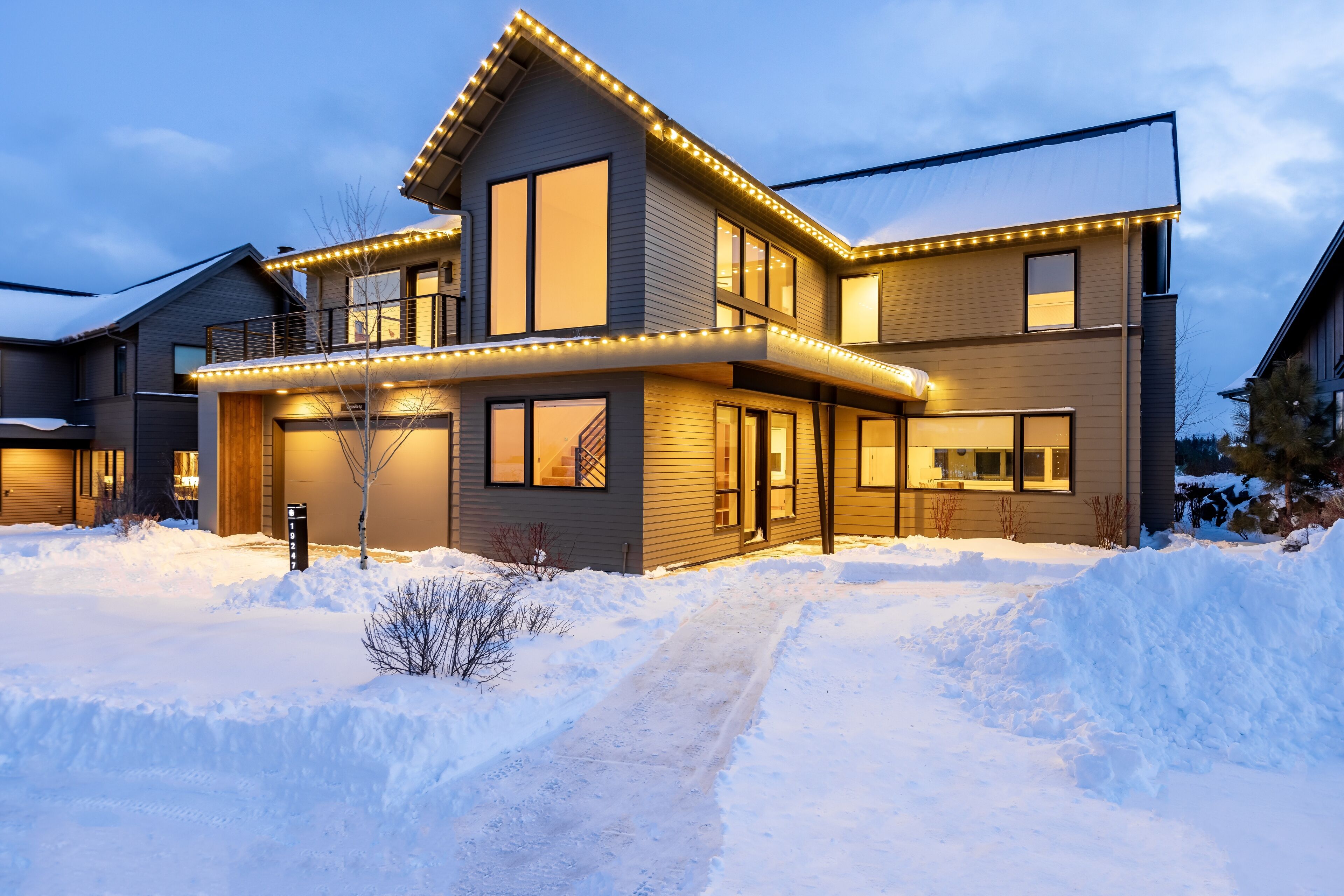 A modern two-story house with a covered porch and a snow-covered driveway.