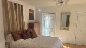 A bedroom with a large bed, wooden dresser, and a chandelier. - The Charming Country Cottage-Welcomes you and your pet! (La Plata)