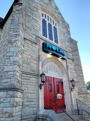 Un bâtiment en pierre avec une porte rouge et une enseigne indiquant « Noche Mexican Bar ».