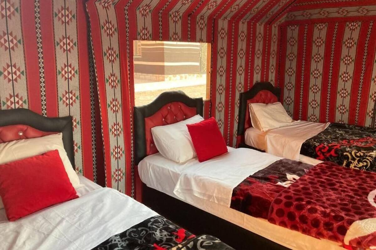 A room with two beds, each with a headboard, and patterned walls.