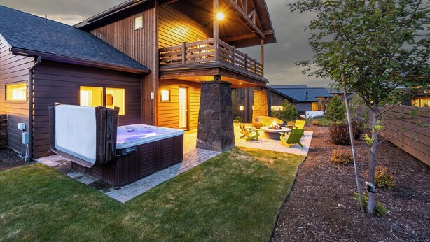 A two-story wooden cabin with a hot tub, outdoor seating, and a stone fireplace. - Bring your 🚲~ resort pool ~ amenities ~ trails ~ golf ~ hot tub ~ Bend ~ 🐶 (Bend)