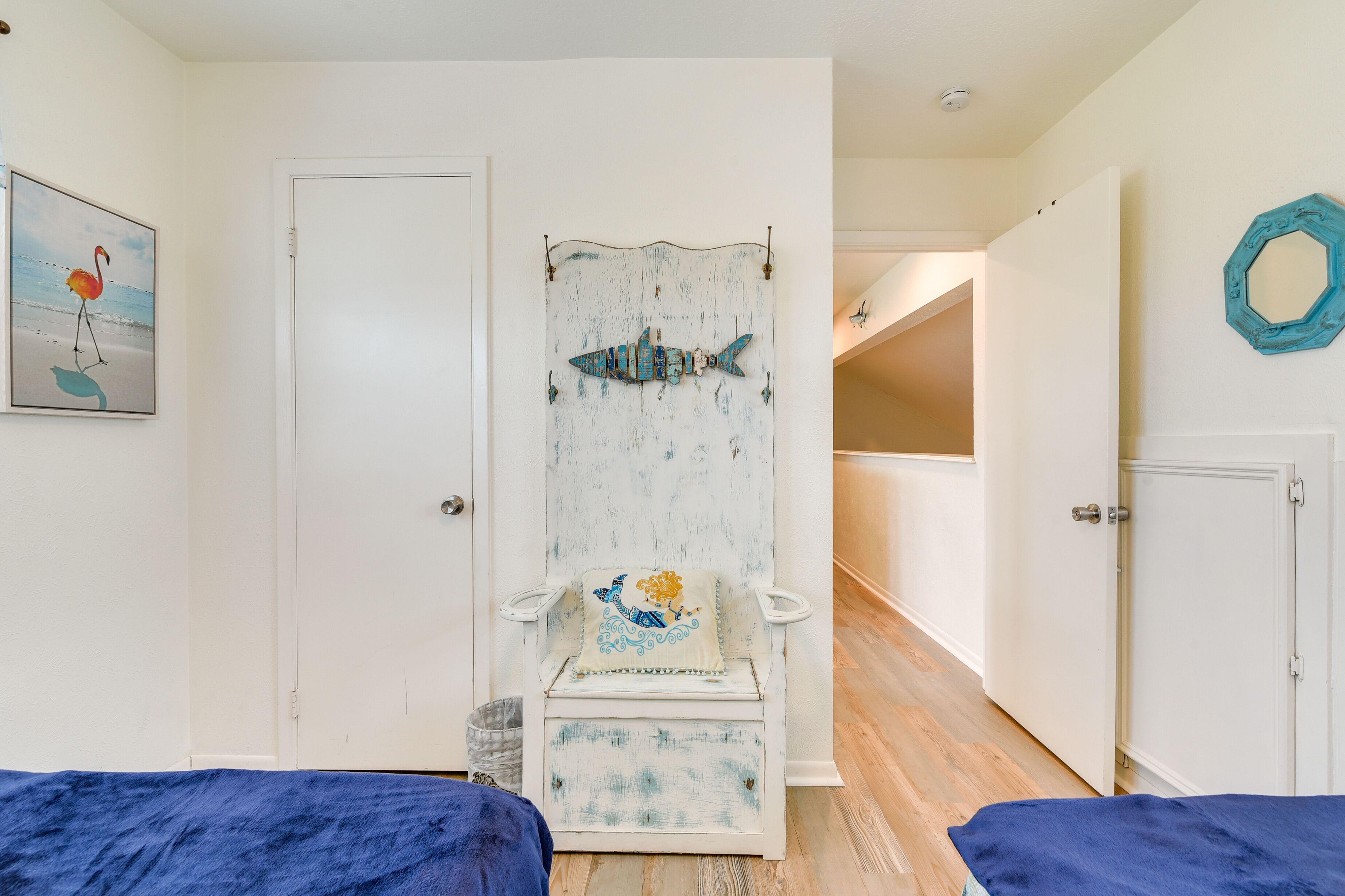A room with a white door, a blue chair with a fish design, and a blue blanket on the floor.