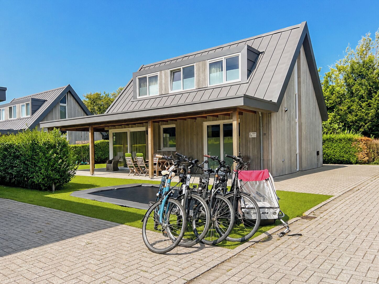 A modern building with a covered patio area, bicycles parked outside, and a well-maintained lawn.