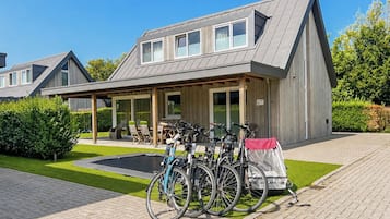 A modern building with a covered patio area, bicycles parked outside, and a well-maintained lawn.