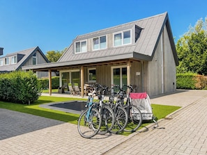 A modern building with a covered patio area, bicycles parked outside, and a well-maintained lawn.