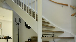 A staircase with wooden steps and white railings, leading to an upper floor.