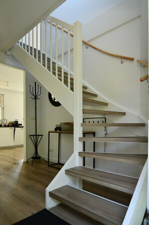 Una escalera de madera con barandillas blancas que conduce a un piso superior.