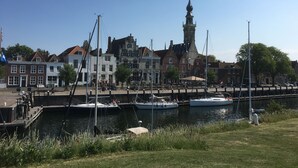 A marina with boats docked, a prominent tower, and historic buildings with red and white facades.