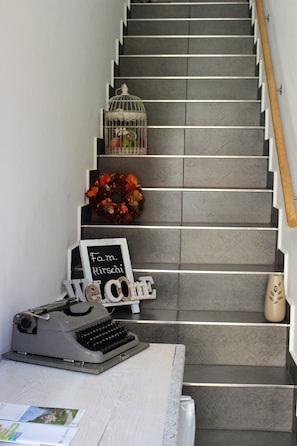 A staircase with a welcome sign, a typewriter, a birdcage, and a wreath. - Mini apartment with terrace (without kitchen!) (Dino-Lugano)