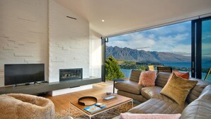 A modern living room with a large TV, a fireplace, and a sofa with cushions.