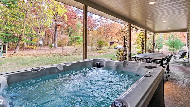 A hot tub in a covered outdoor area with a view of autumn trees. - Dog-Friendly Cottage with Hot Tub (Pullman)