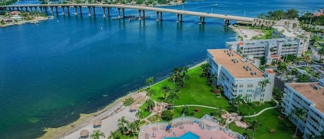 Un resort con piscina, acceso directo a la playa y un puente al fondo.