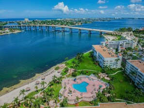 Un resort con piscina, acceso directo a la playa y un puente al fondo.