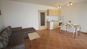 A compact living space with a sofa, a small table, a dining area with chairs, and a kitchenette. - Holiday apartment with sea view and barbecue facilities (Šilo)