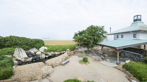 A landscaped garden with a pond, seating areas, and a building with a green roof. - Sanuki mansion (Kanonji)