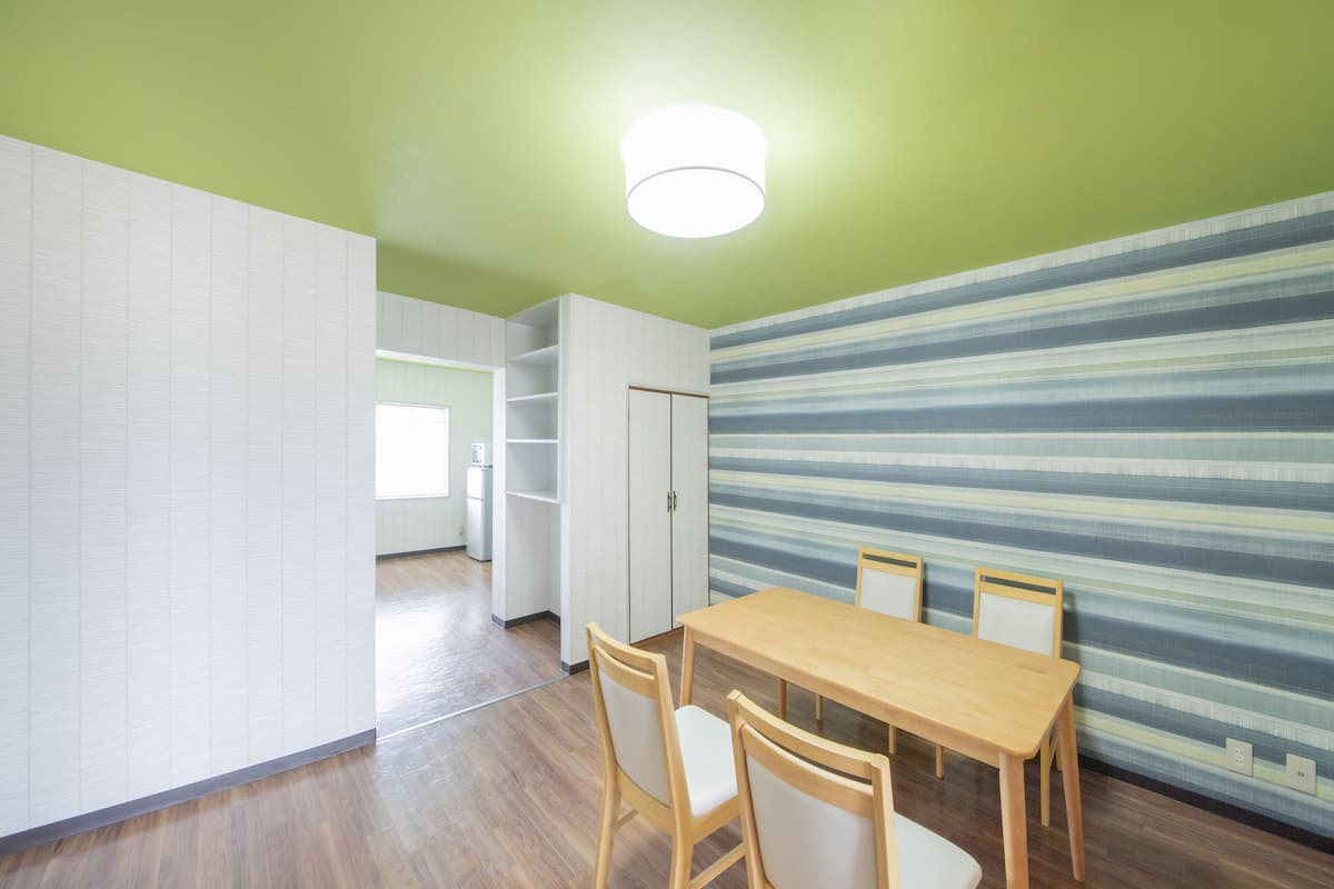 A dining area with a wooden table and chairs, a striped wall, and a white cabinet.