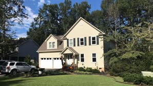 A two-story house with a front porch, garage, and a well-maintained lawn. - Masters Rental Conveniently Located to Augusta National (Aiken)