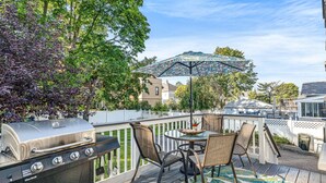 A patio with a grill, outdoor table, chairs, and a patterned rug.