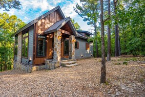 Une cabane avec des fondations en pierre, un revêtement extérieur en bois et une véranda dotée de piliers en pierre.