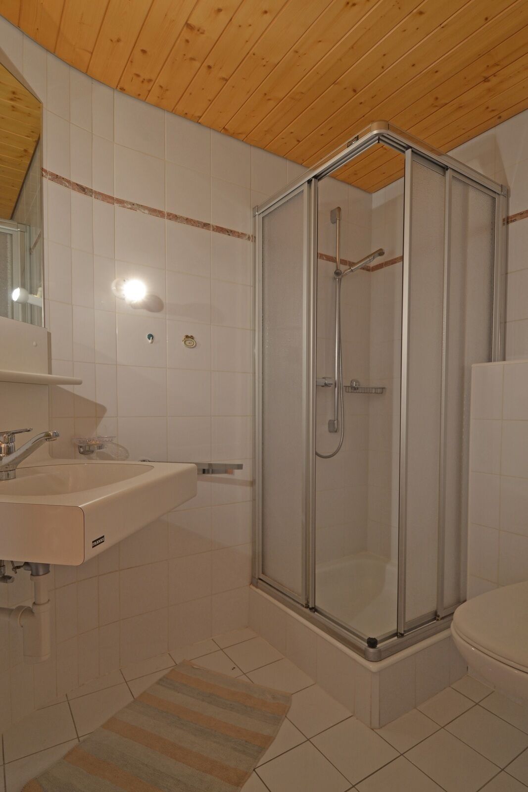 A bathroom with a glass-enclosed shower, a sink, and a toilet.