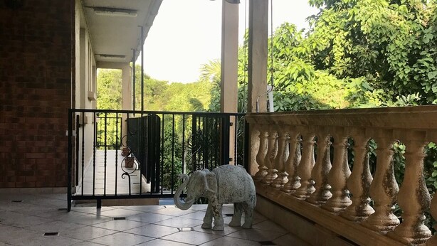 Un espace extérieur abrité, doté d’un sol carrelé, d’un portail en métal et d’une statue d’éléphant décorative.