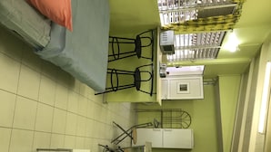 Une pièce comprenant un lit, un bureau, une chaise, un radiateur, une fenêtre et une porte.