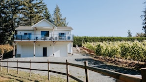Un bâtiment à deux étages doté d’un balcon, entouré d’un vignoble.