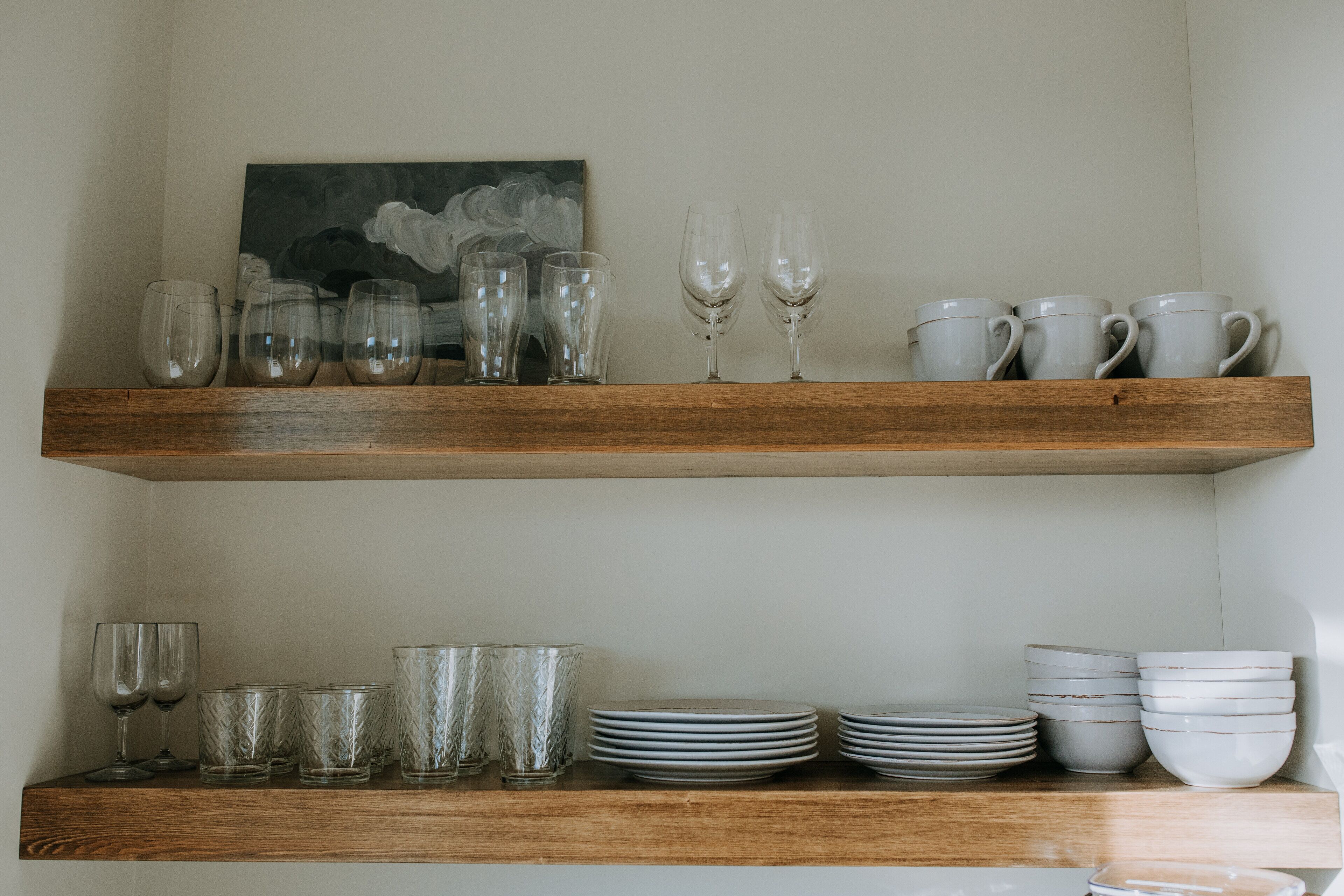 Two wooden shelves with various glassware and plates.