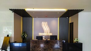 A reception desk with a marble top, a digital screen, and a logo for 'SOTOGRANDE'. - Sotogrande Neopolitan Hotel (Quezon City)
