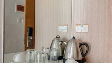 Une chambre d’hôtel dotée d’un coin cuisine comprenant une bouilloire, une théière et des tasses, le tout posé sur un comptoir.