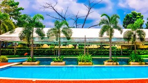 A swimming pool with palm trees and a covered area. - Sotogrande Neopolitan Hotel (Quezon City)