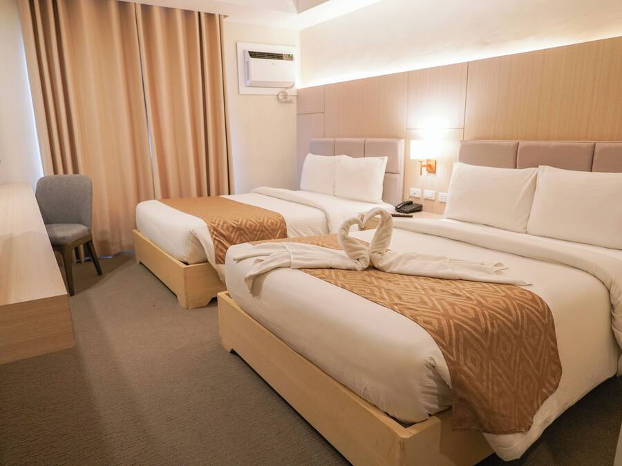 Ett hotellrum med två sängar, ett skrivbord, en stol och en lampa.