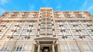 A multi-story hotel with a symmetrical facade, balconies, and a central entrance with steps. - Sotogrande Neopolitan Hotel (Quezon City)