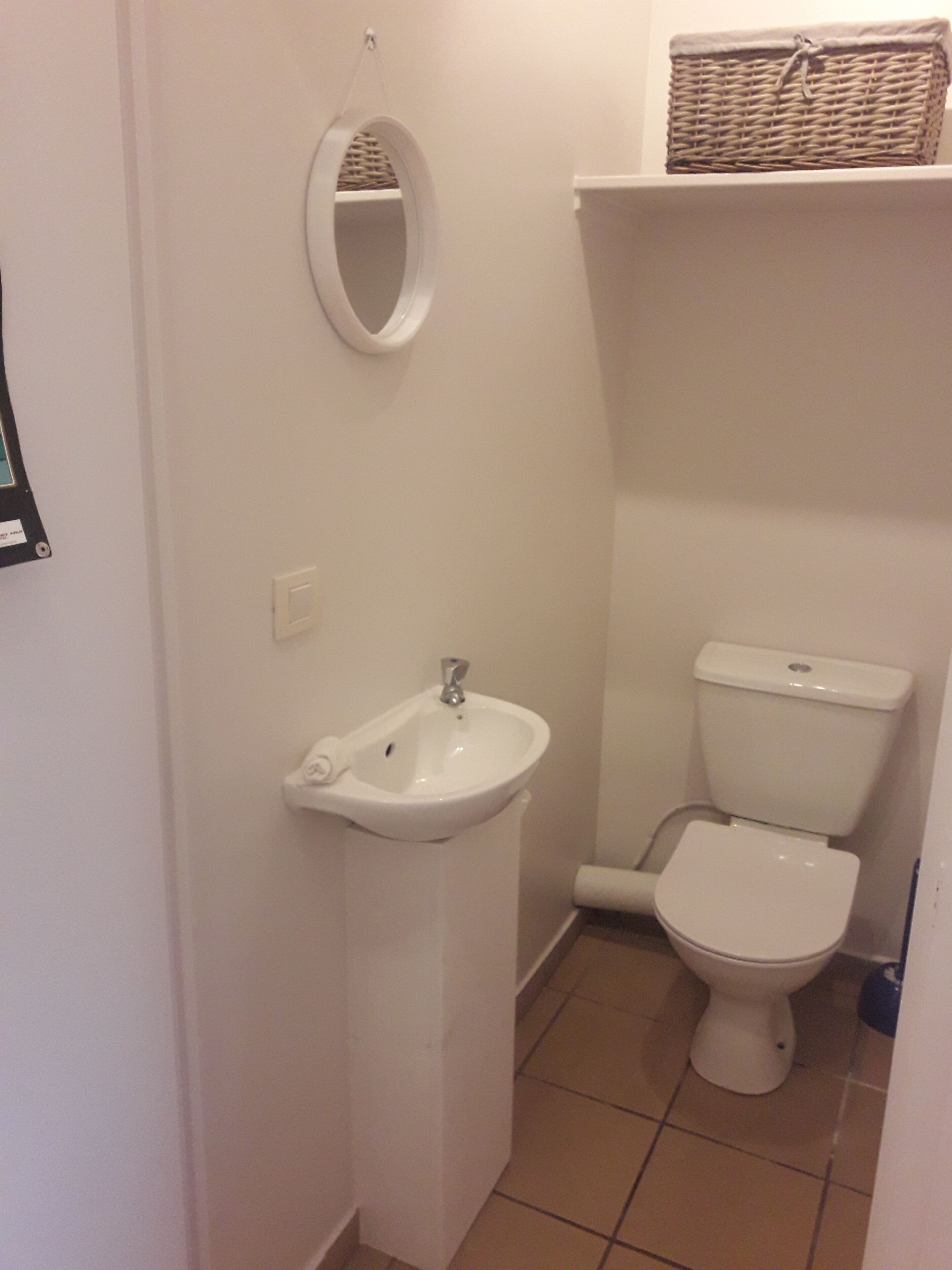 Une petite salle de bain avec un lavabo blanc, des toilettes et un miroir.