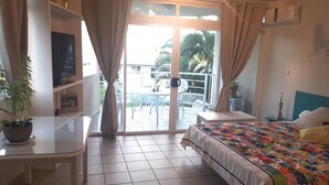 Ein Hotelzimmer mit Bett, Schreibtisch, Stuhl und einem Balkon mit Tisch und Stühlen.