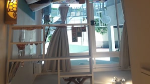 Ein Zimmer mit einem Holzkabinett, einem weißen Regal, einer farbenfrohen Steppdecke und einem Fenster mit Vorhängen.