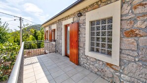 A stone building with a balcony, a window with a grid pattern, and a door with wooden shutters. - Holiday home mit Pool und Klimaanlage (Barci)