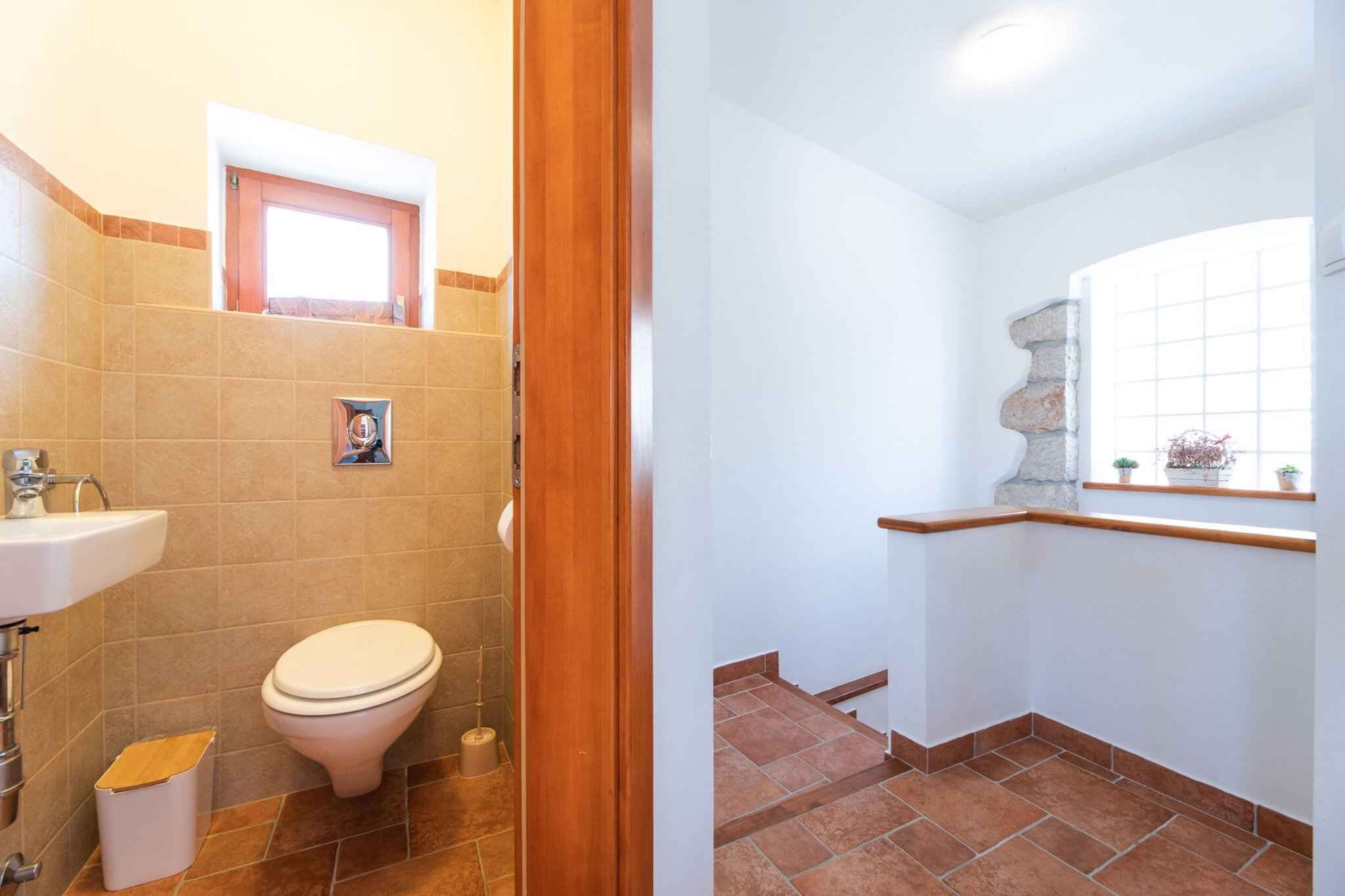 A bathroom with a toilet, sink, and a small window.