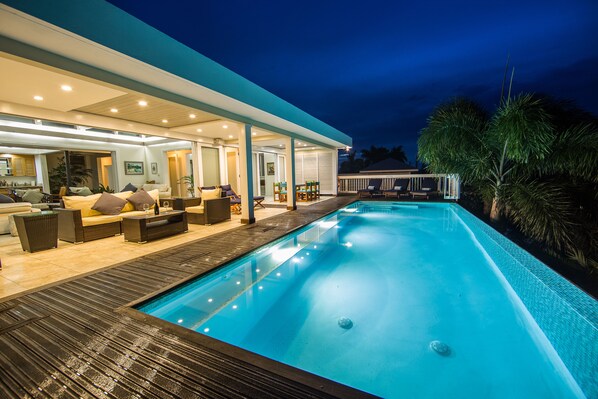 A modern outdoor pool area with a covered seating area and a poolside bar.