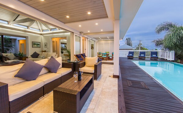 A modern outdoor living area with a pool, comfortable seating, and a covered patio. - Luxury 4BR Villa in Silver Sands Beach Resort, Trelawny, Jamaica (Duncans)